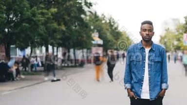 孤独的非裔美国男生手插口袋站在大城市的步行街上